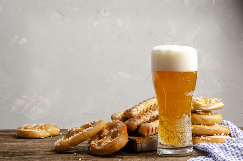 a glass of beer next to a stack of pretzels