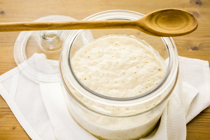 Sourdough starter in large glass jar on the table.